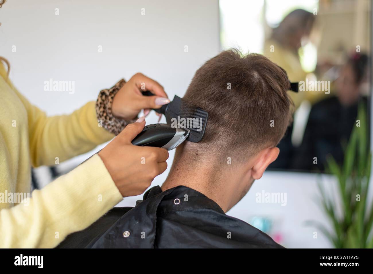 Un coiffeur concentré donnant à un client une coupe de cheveux fraîche. Banque D'Images