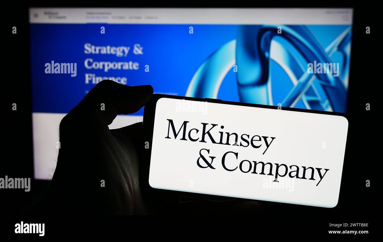 Personne tenant le téléphone portable avec le logo de l'entreprise américaine de conseil McKinsey and Company en face de la page Web. Concentrez-vous sur l'affichage du téléphone. Banque D'Images