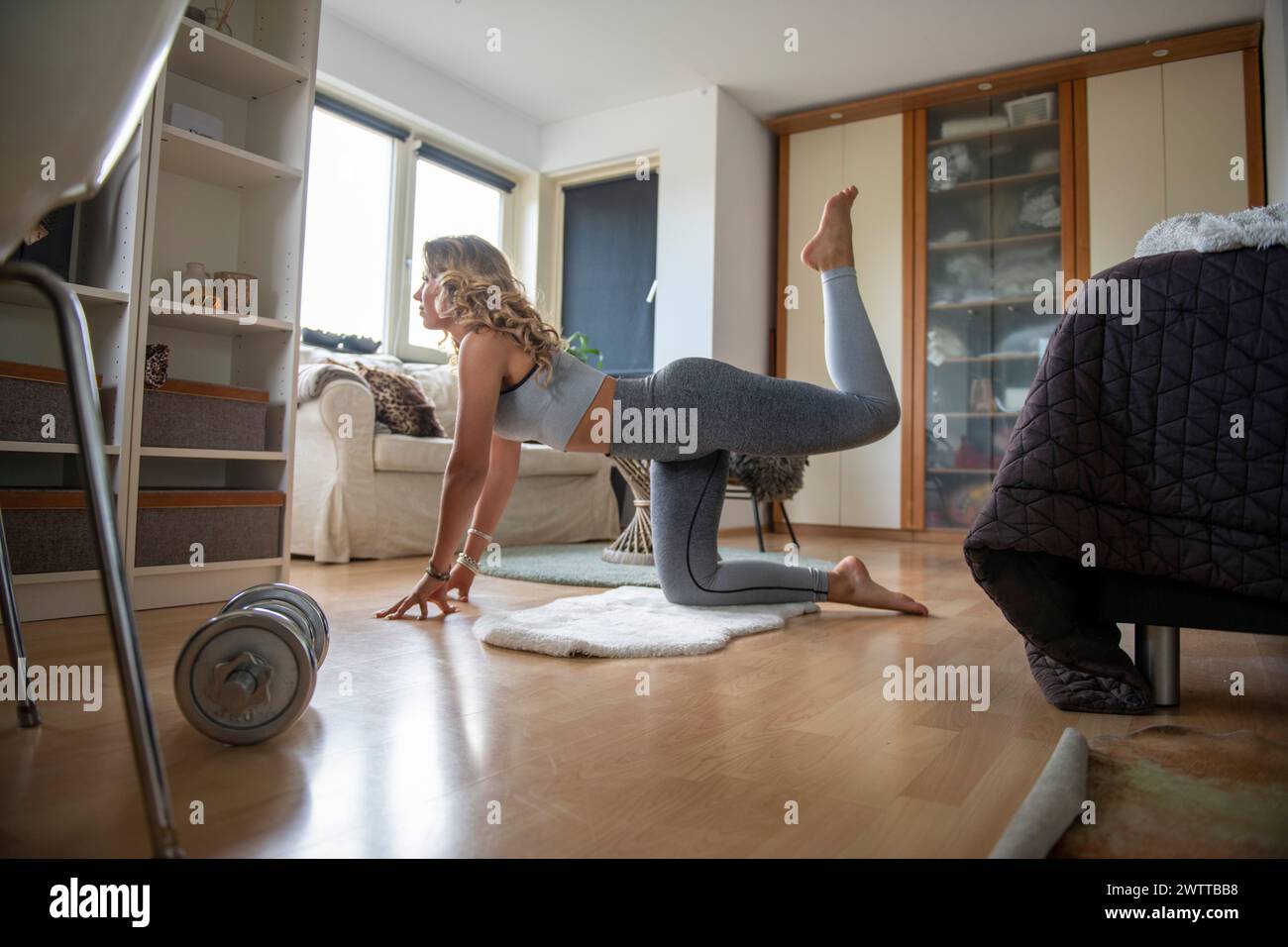 Une femme pratiquant le yoga à la maison dans un salon confortable. Banque D'Images