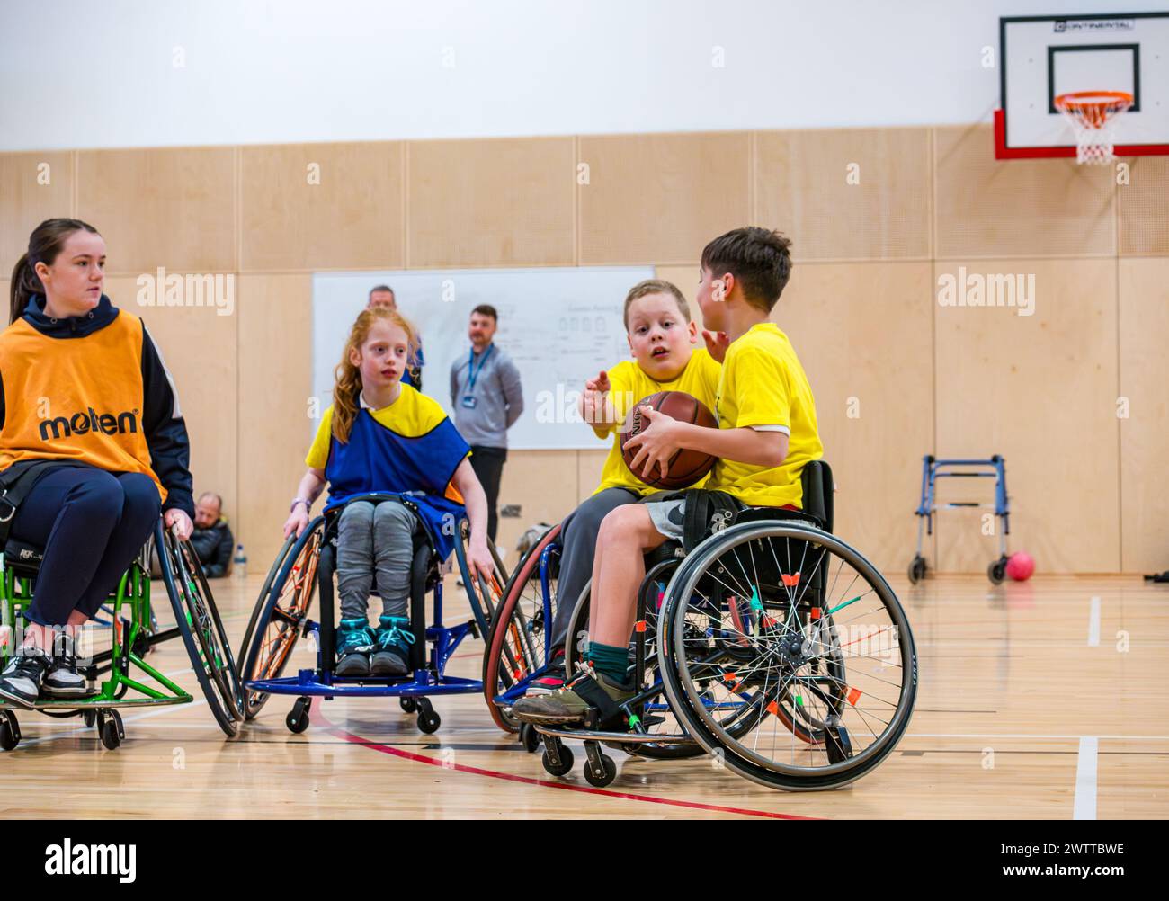 Winchburgh Academy, West Lothian, Écosse, Royaume-Uni, 19 mars 2024. Festival Parasport pour les enfants handicapés : Scottish Disability Sport organise une série de manifestations à l'échelle nationale pour offrir aux jeunes handicapés physiques, malentendants et malvoyants la possibilité d'essayer un large éventail de sports dispensés par des entraîneurs qualifiés locaux. Photo : les enfants essaient le basketball en fauteuil roulant même s'ils n'utilisent pas de fauteuil roulant. Crédit : Sally Anderson/Alamy Live News Banque D'Images