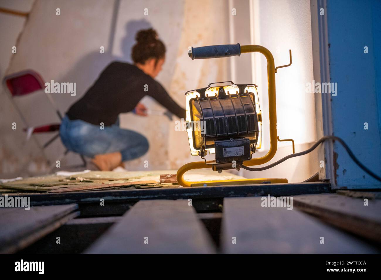 Un passionné de bricolage concentre peint un mur dans une pièce en cours de rénovation. Banque D'Images