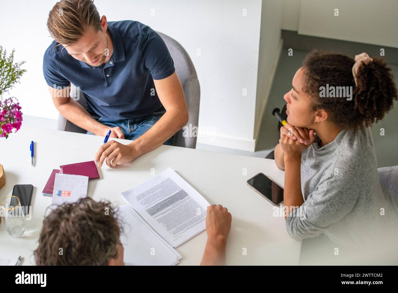 Adulte expliquant un document à une jeune fille curieuse à une table. Banque D'Images