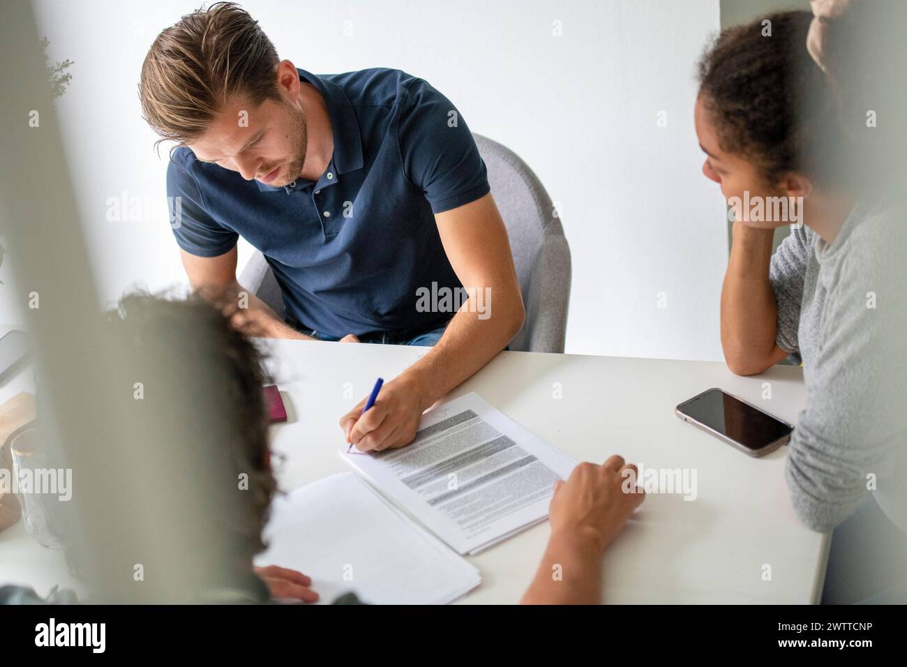 Les membres de l'équipe concentrés examinent les documents à une table blanche. Banque D'Images