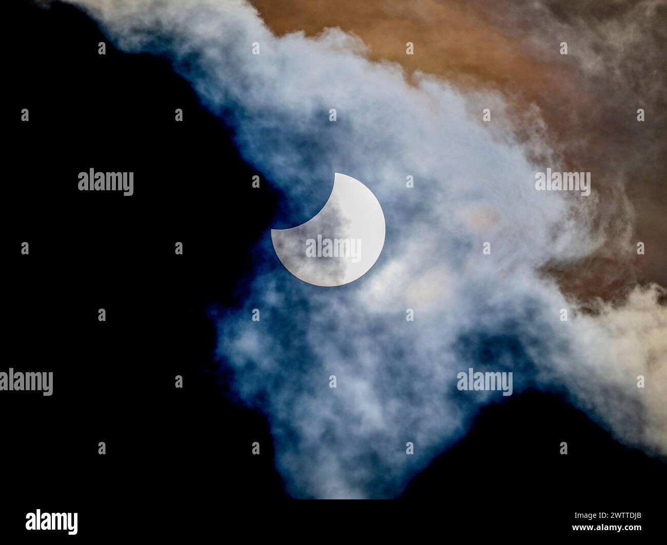 Éclipse solaire partielle essayant à travers des nuages sinueux Banque D'Images