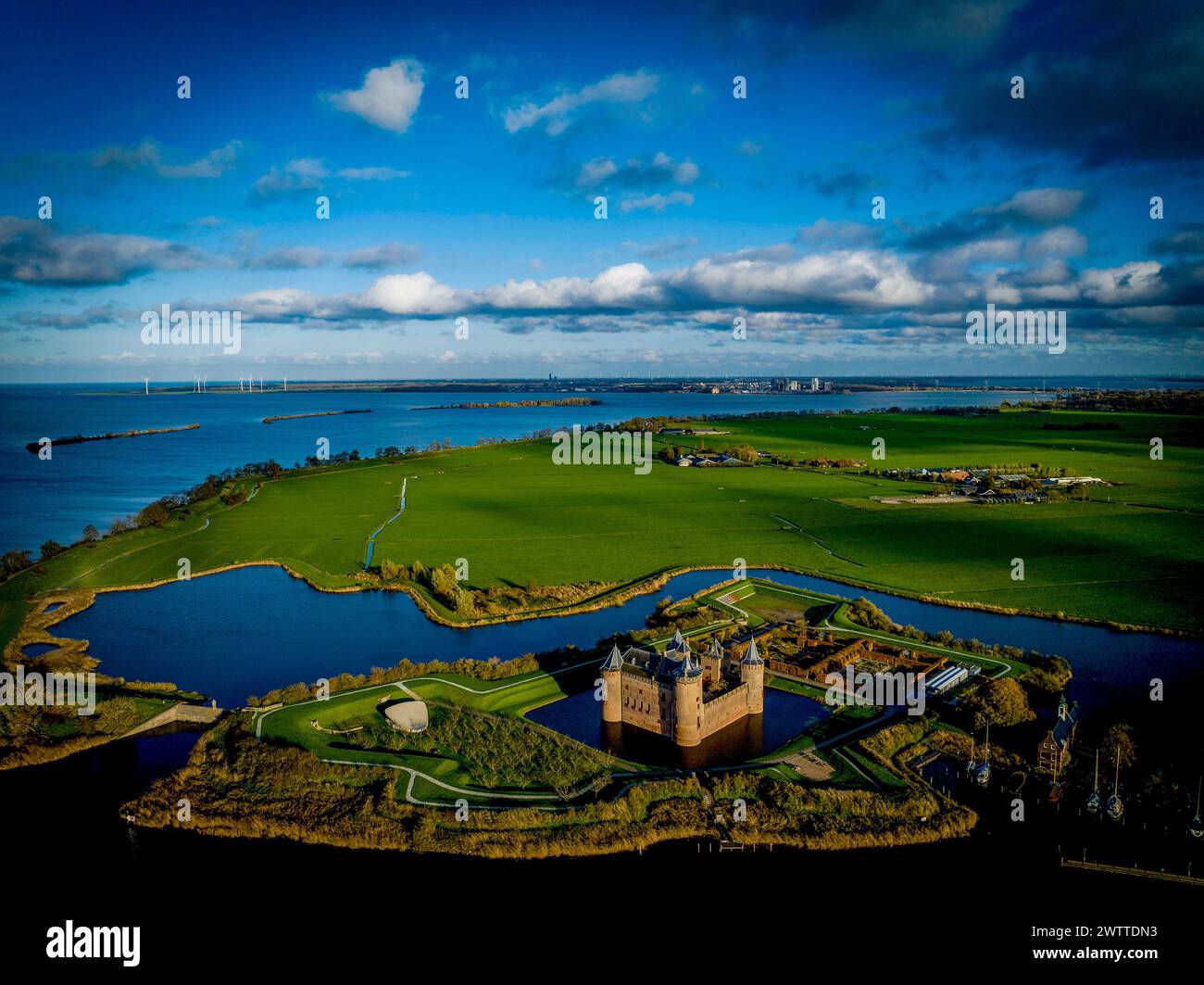 Vue aérienne d'un ancien château entouré de douves dans un paysage verdoyant sous un ciel bleu avec des nuages. Banque D'Images