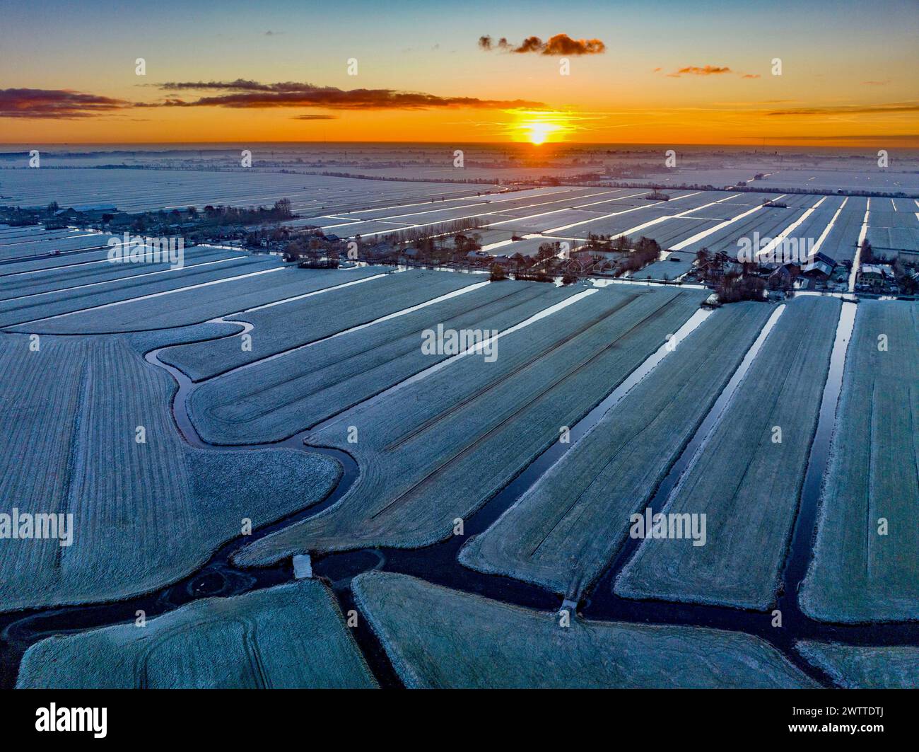 Vue aérienne d'un paysage enneigé au coucher du soleil avec des teintes dorées touchant les champs givrés Banque D'Images