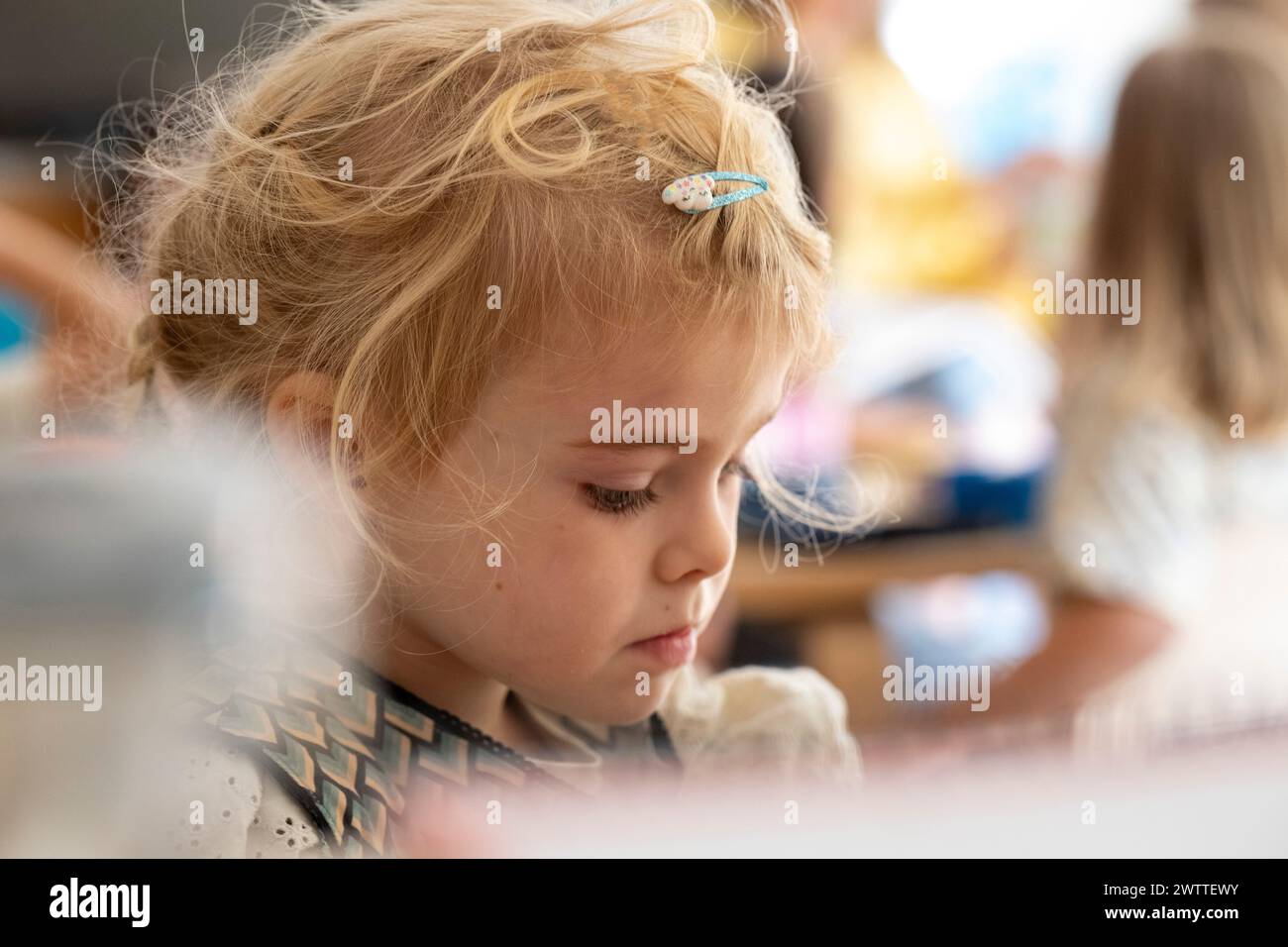 Petite fille concentrée sur une tâche créative à l'heure de jeu. Banque D'Images