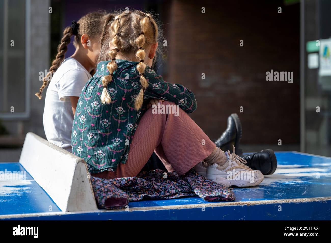 Deux jeunes filles assises ensemble dans la conversation par une journée ensoleillée. Banque D'Images