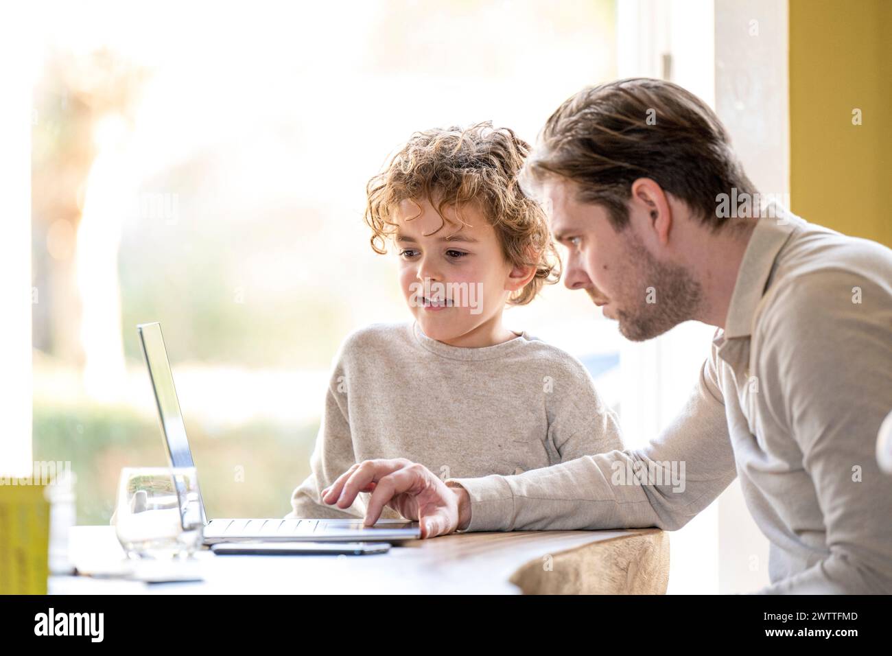 Père et enfant se sont concentrés sur une tâche informatique ensemble. Banque D'Images