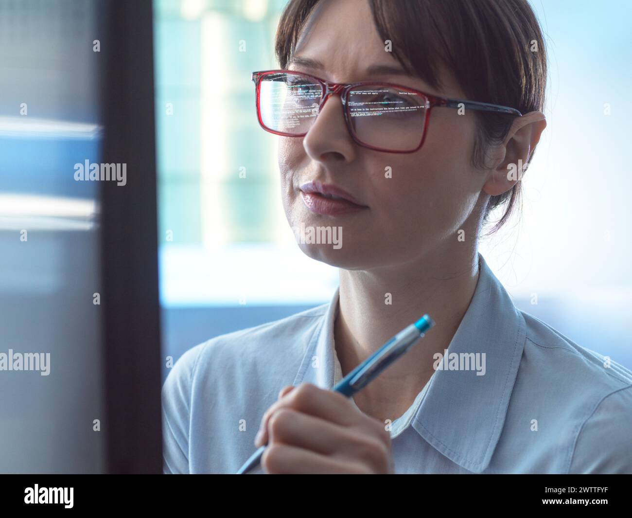 Programmeur féminin concevant du code sur un écran d'ordinateur dans le bureau. Banque D'Images