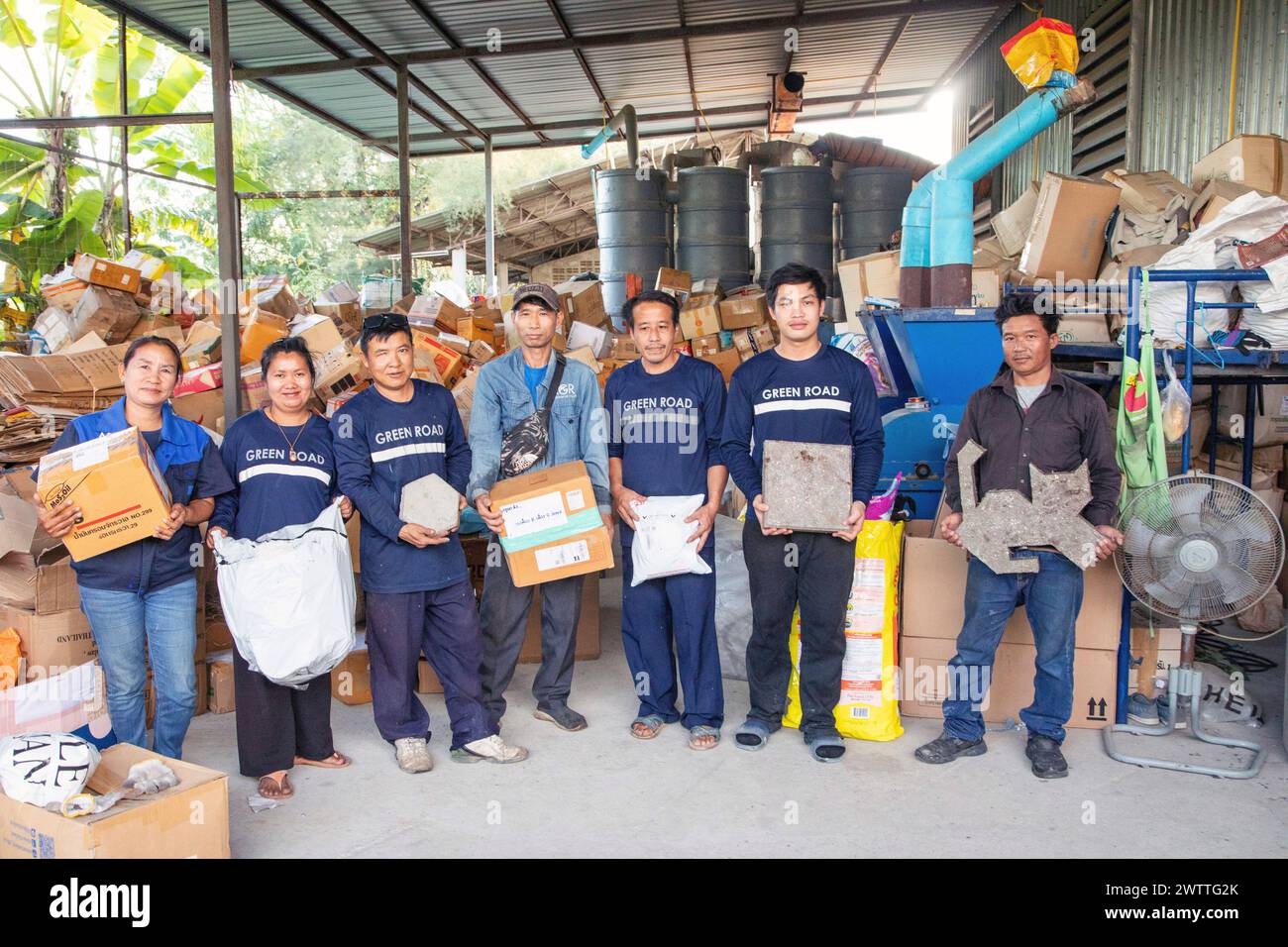 Équipe de recyclage fièrement debout dans leur espace de travail avec des matériaux prêts pour le traitement, Thaïlande Banque D'Images