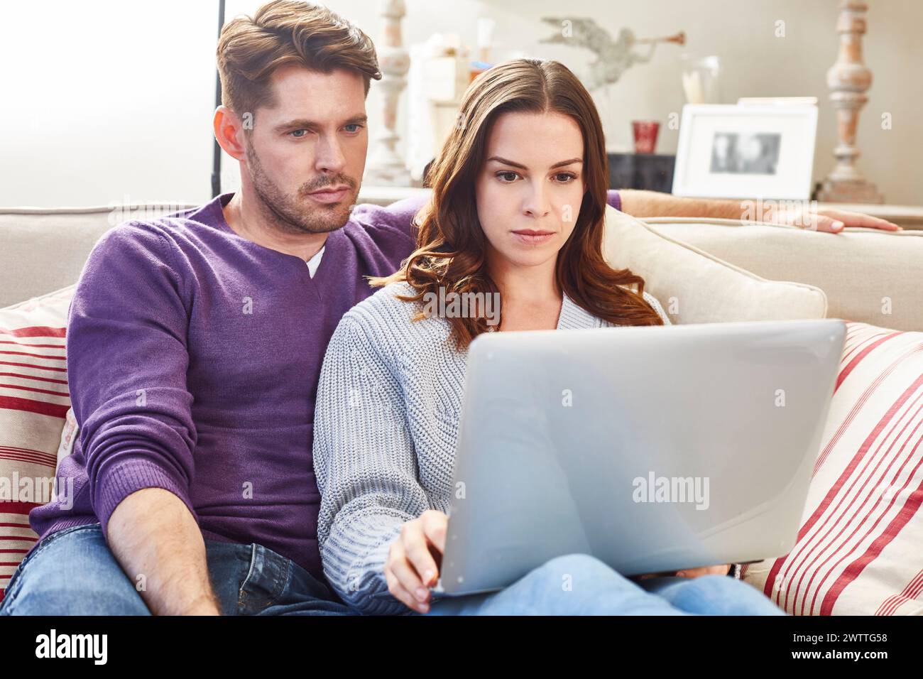 Couple assis sur un canapé à l'aide d'un ordinateur portable. Banque D'Images