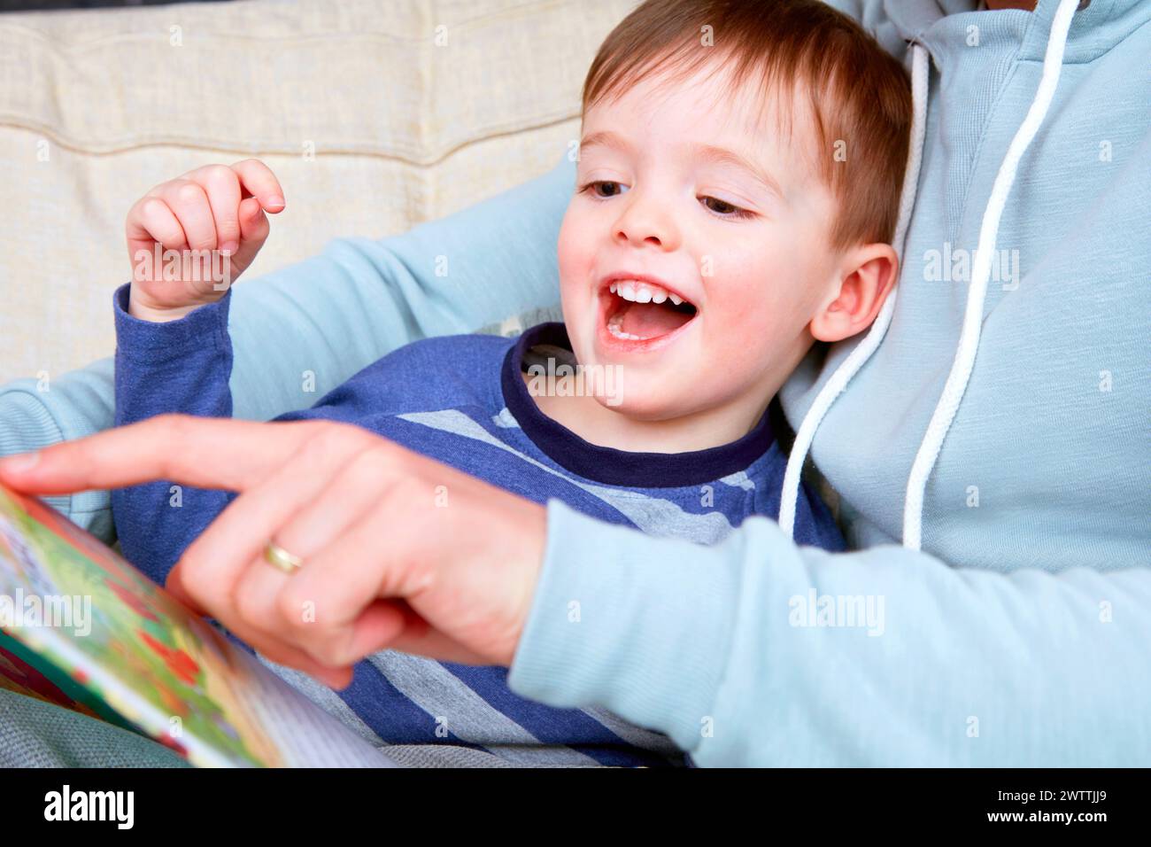 Enfant lisant un livre excité avec un adulte Banque D'Images