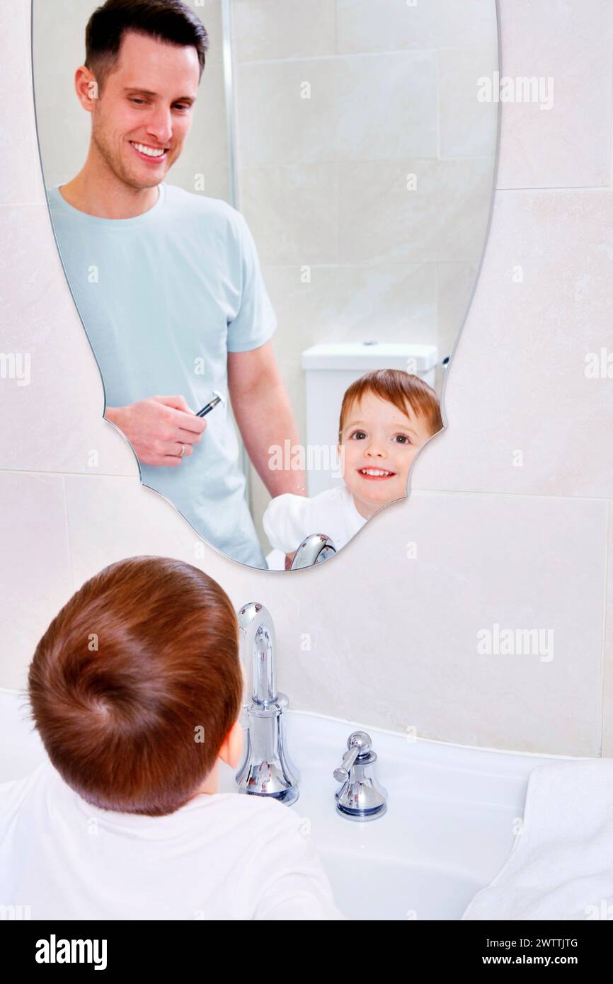 Homme et enfant reflétés dans le miroir de la salle de bain Banque D'Images