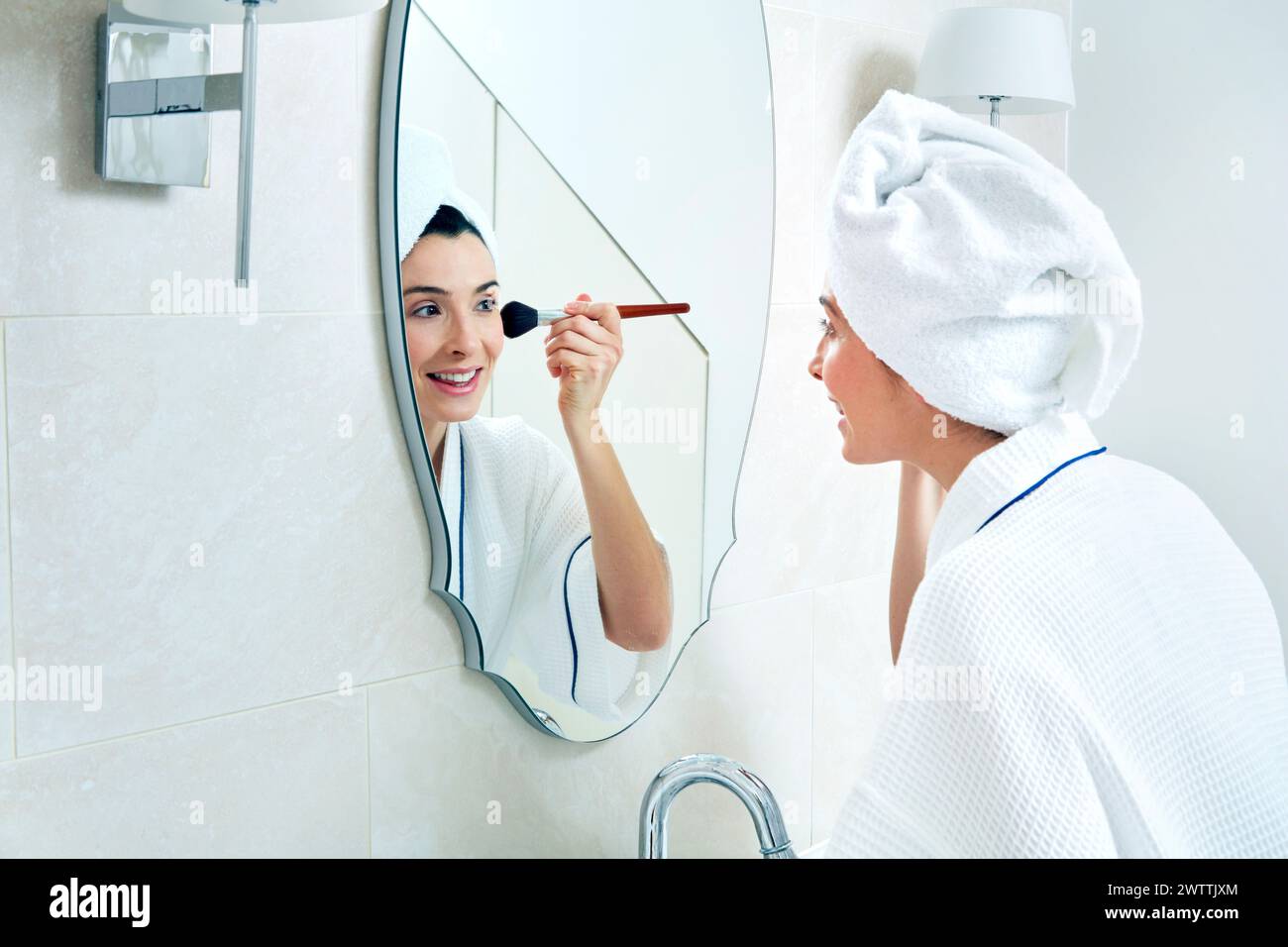 En appliquant le maquillage femme miroir de salle de bains Banque D'Images