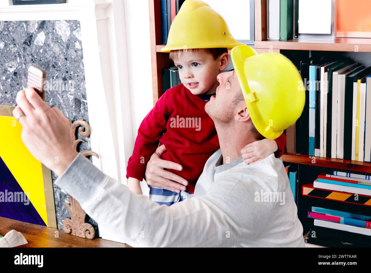 Adulte et enfant portant un casque de sécurité prenant un selfie. Banque D'Images