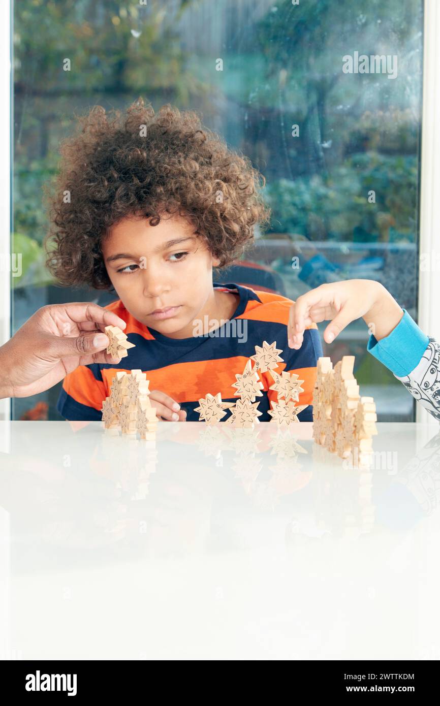 Enfant jouant avec des pièces de puzzle en bois à l'intérieur Banque D'Images