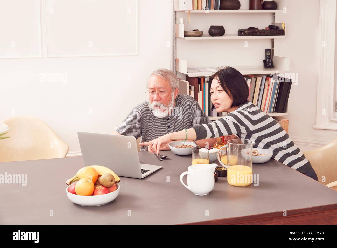 Deux personnes utilisant un ordinateur portable à une table à manger. Banque D'Images