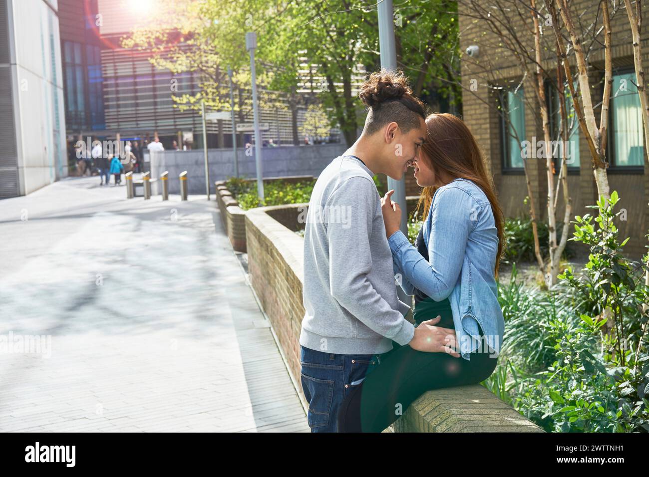 Couple penché pour un baiser sur un trottoir ensoleillé de la ville Banque D'Images