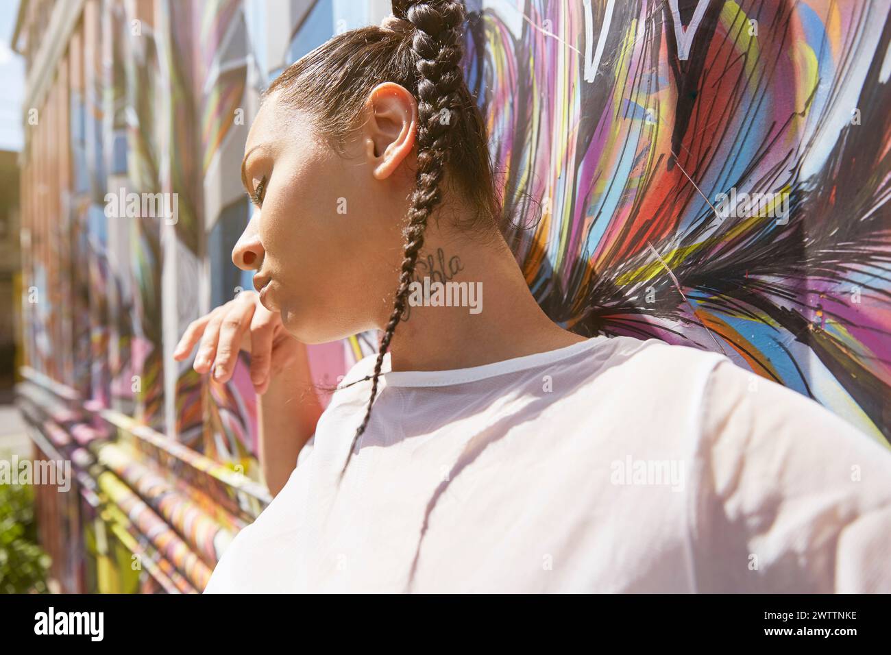 Femme appuyée contre un mur de graffitis coloré Banque D'Images