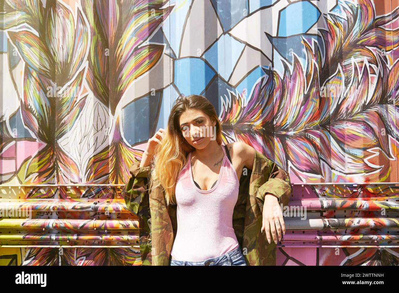 Femme posant devant un mur de graffitis coloré Banque D'Images