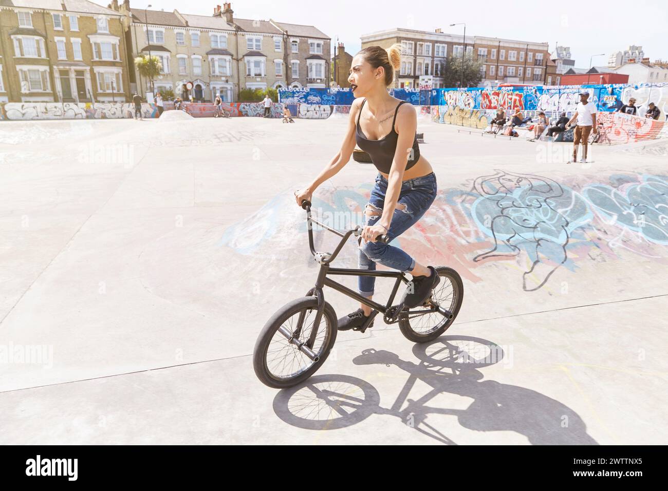 Femme chevauchant un vélo BMX dans un skatepark Banque D'Images