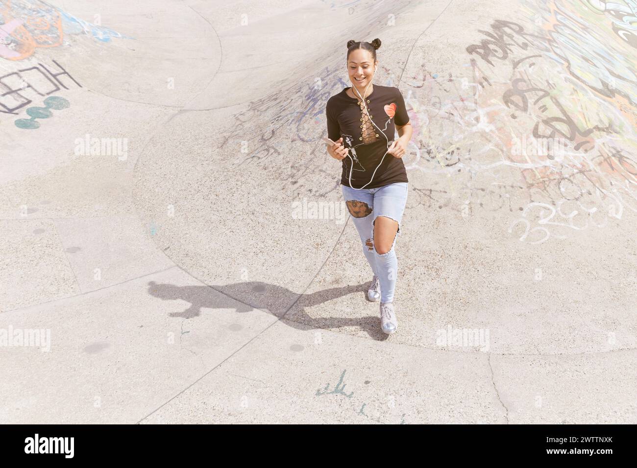 Femme faisant du jogging avec des écouteurs dans une zone couverte de graffitis Banque D'Images