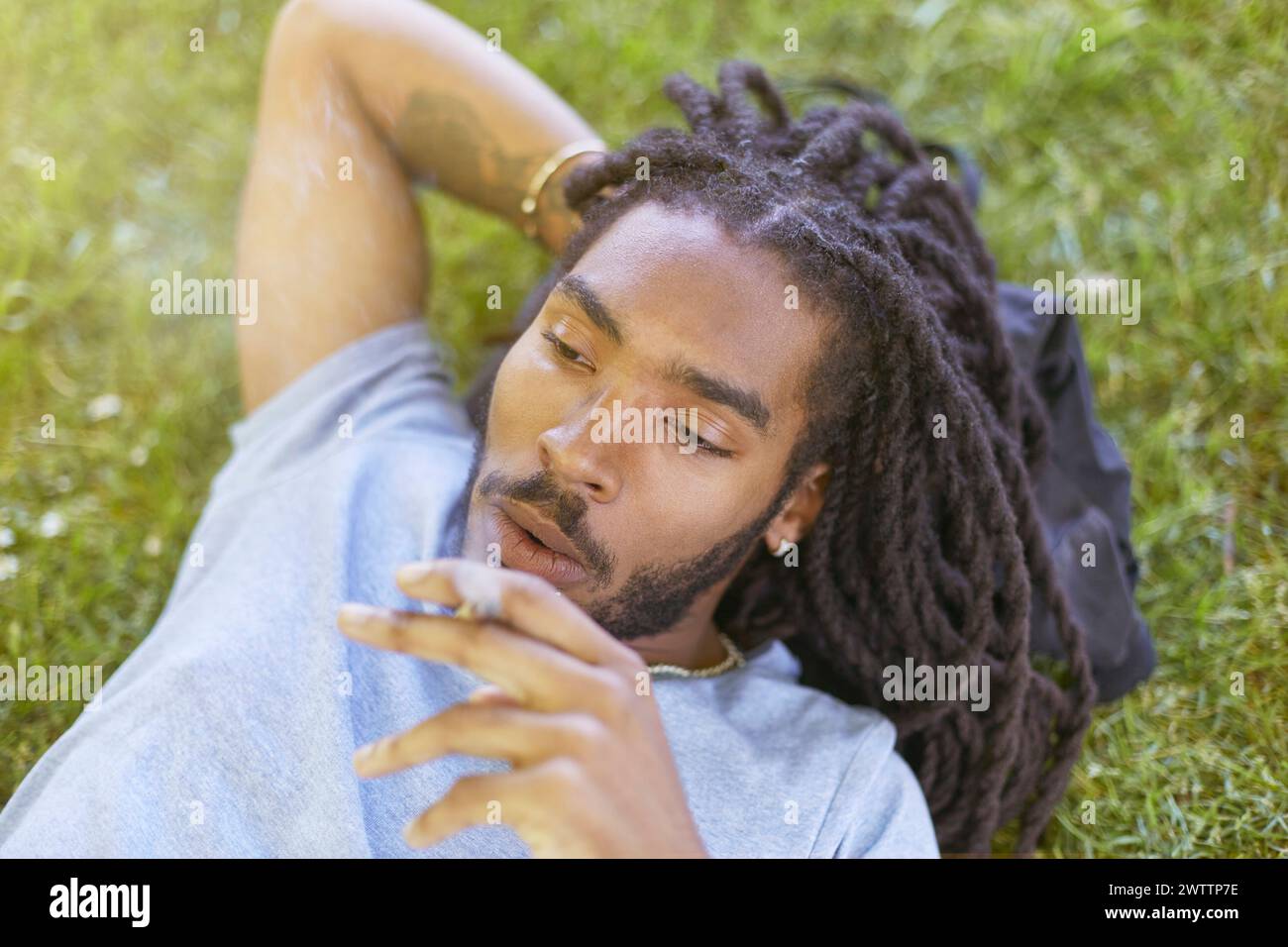 Homme se relaxant dans l'herbe avec une expression réfléchie. Banque D'Images