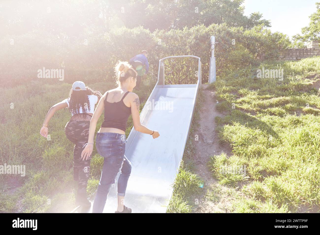 Amis grimpant sur un toboggan dans un parc. Banque D'Images