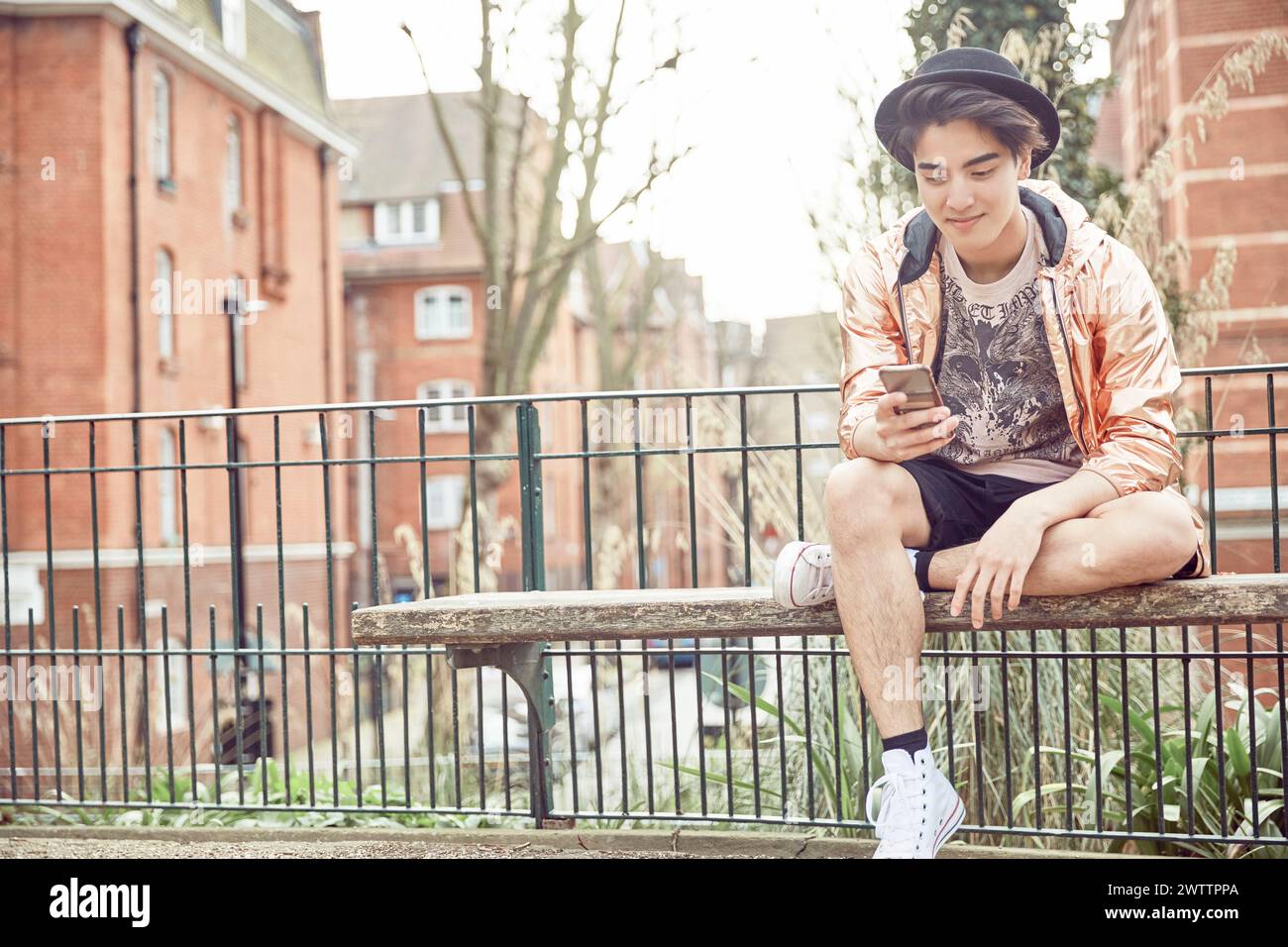 Jeune adulte utilisant un smartphone sur un banc. Banque D'Images