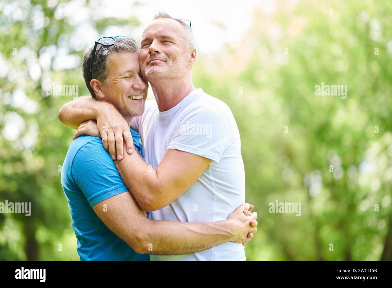 Deux hommes s'embrassant dans un parc ensoleillé Banque D'Images