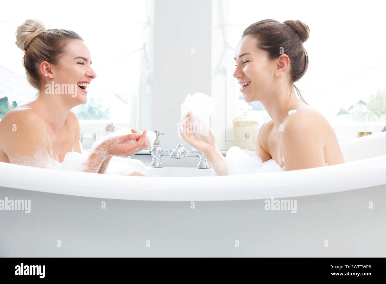 Deux femmes riant dans un bain moussant Banque D'Images