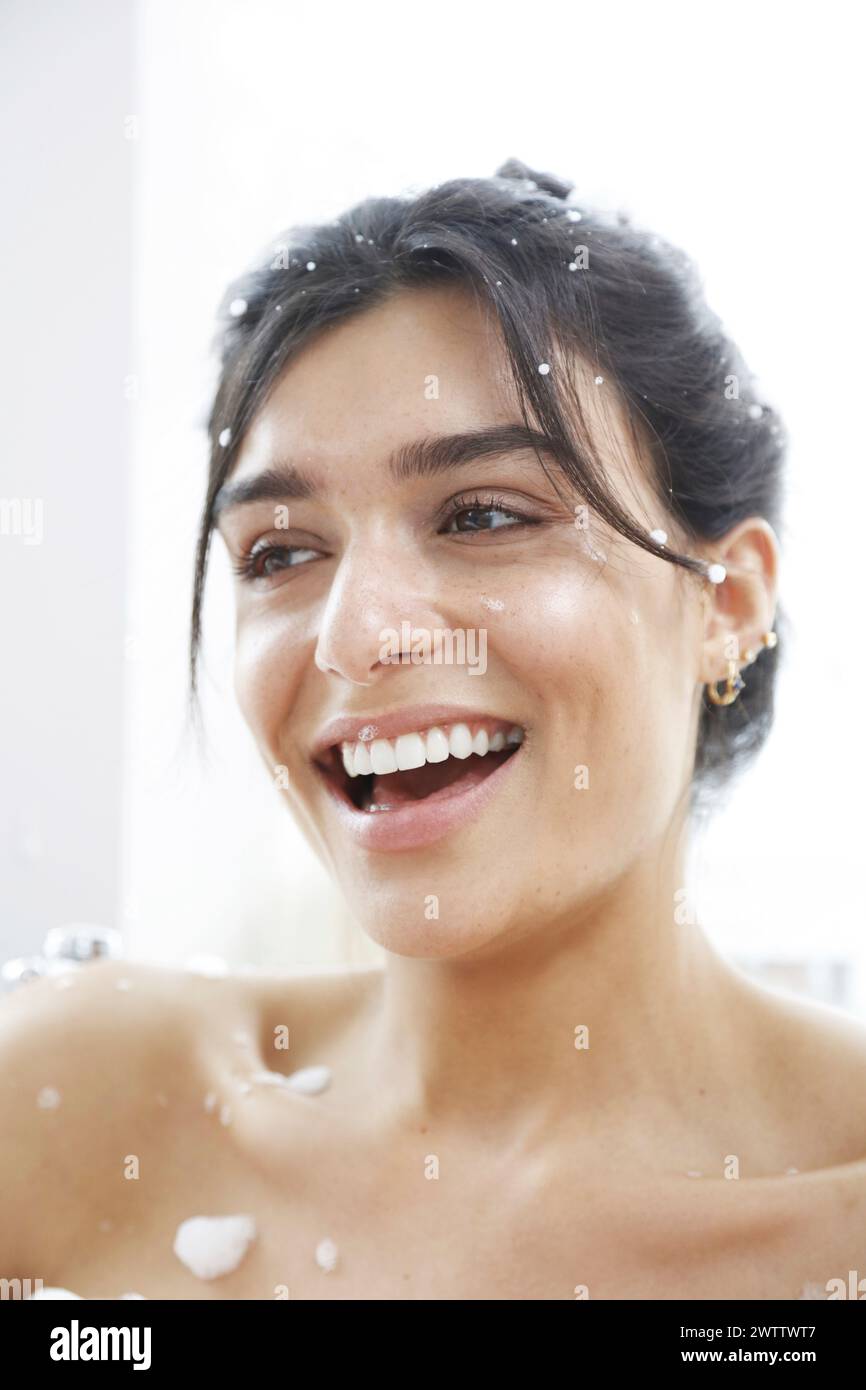 Femme souriant avec des gouttelettes d'eau sur la peau Banque D'Images