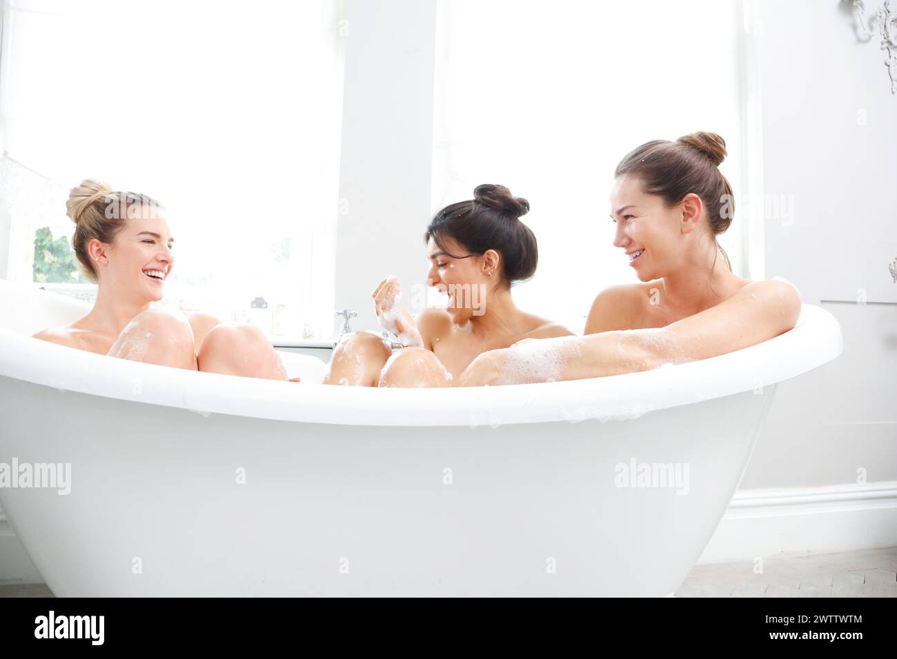 Trois femmes riant dans un bain moussant Banque D'Images