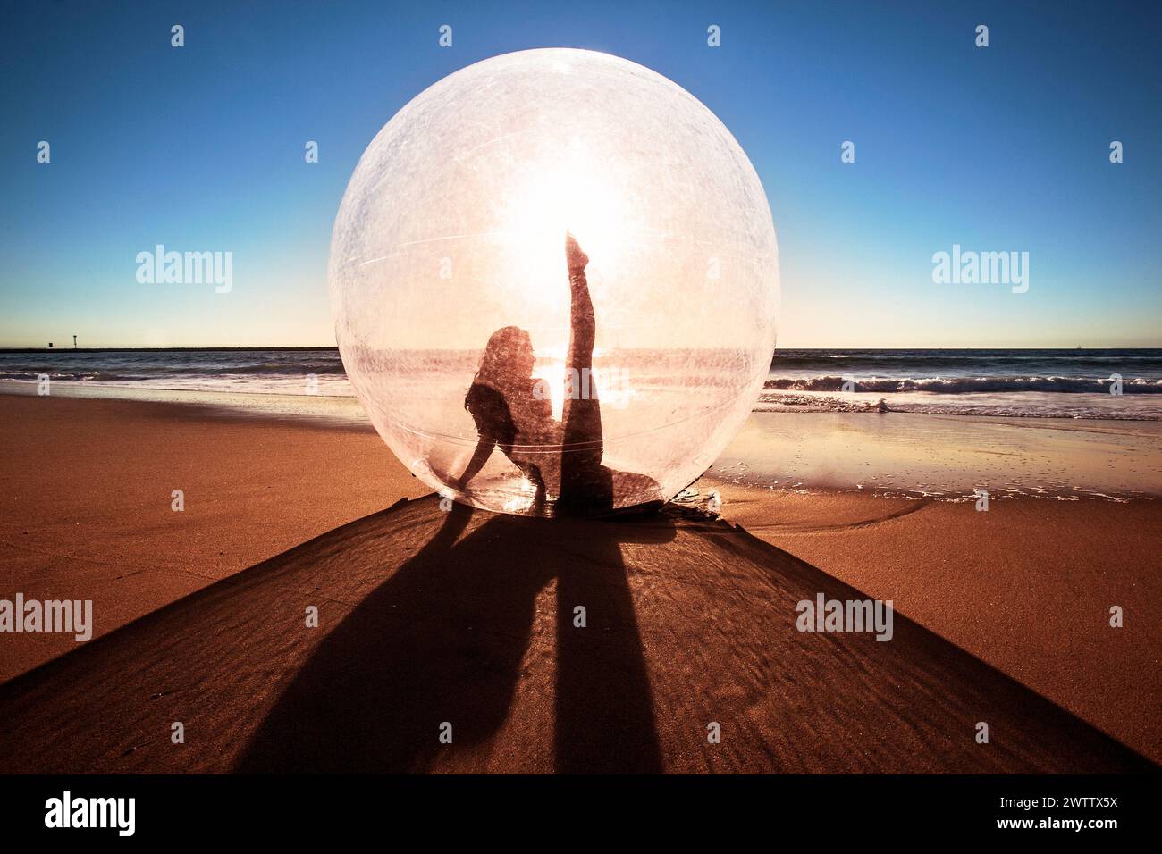 Silhouette à l'intérieur d'une bulle à la plage pendant le coucher du soleil Banque D'Images