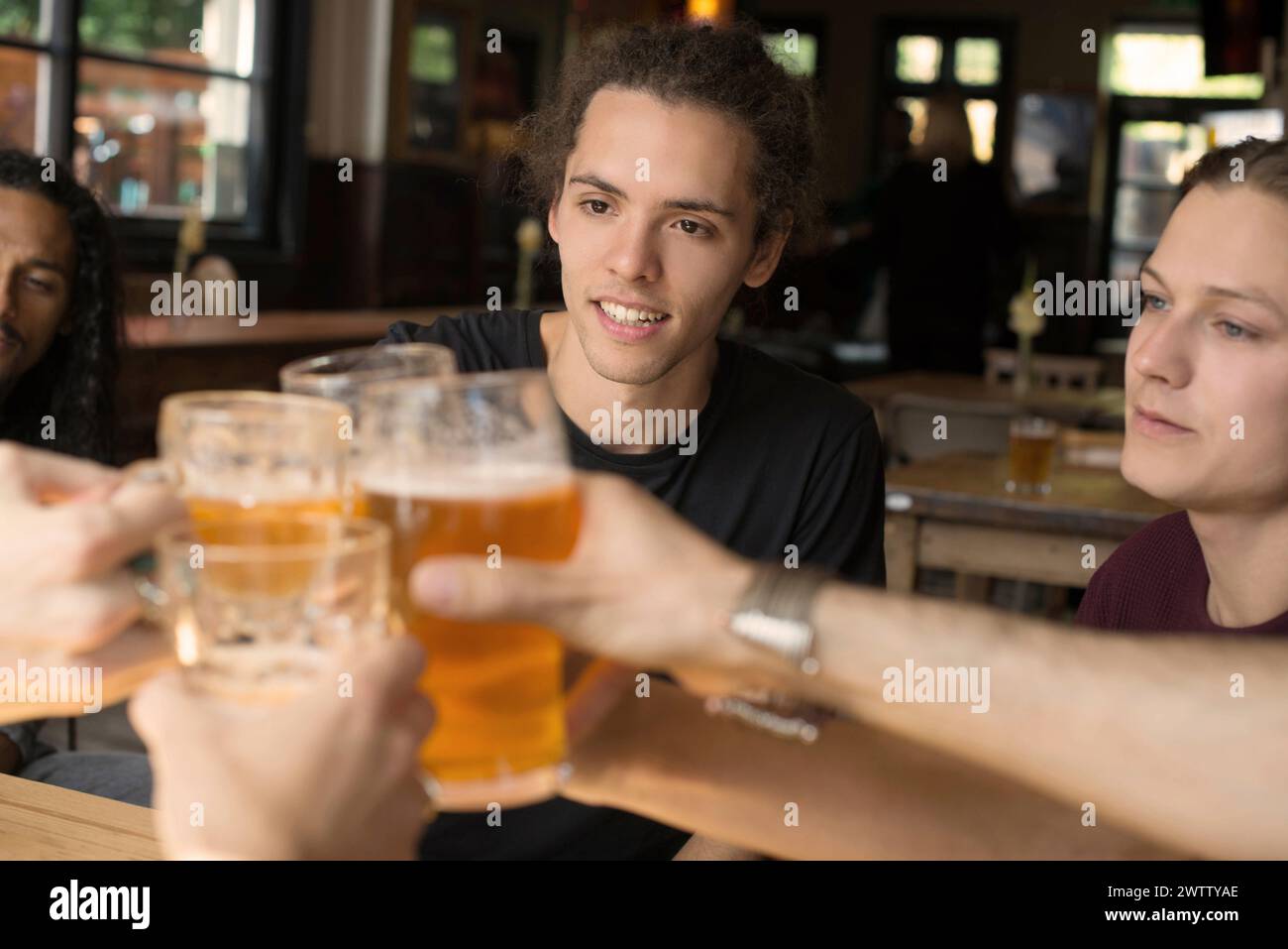 Amis toast avec des verres à bière dans un pub Banque D'Images