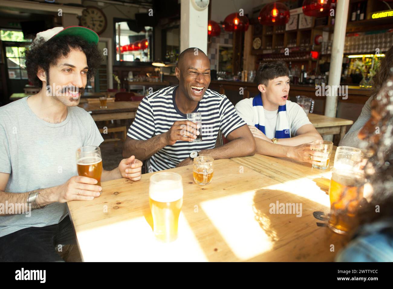 Amis riant ensemble dans un bar Banque D'Images
