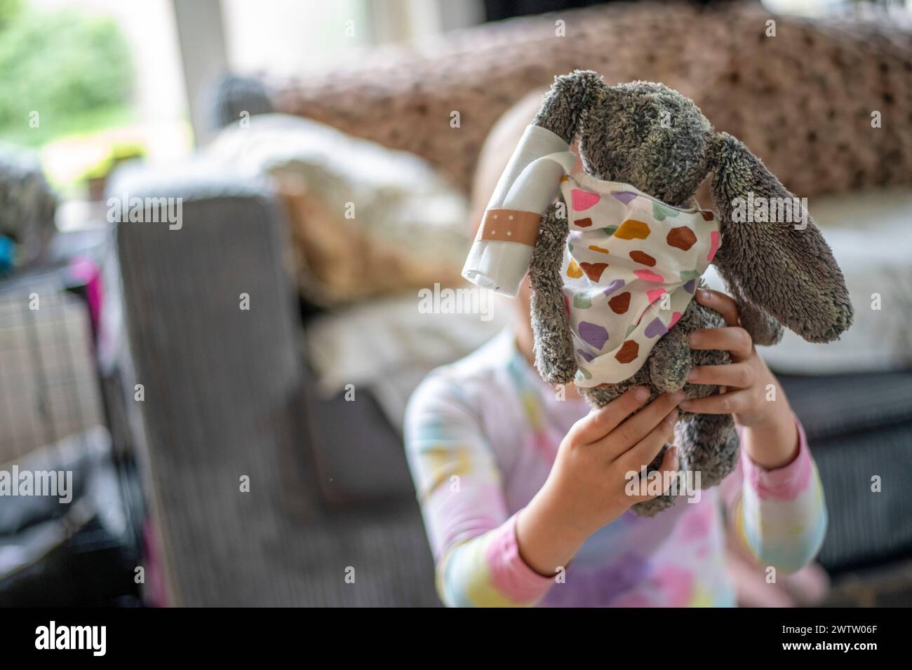 Enfant jouant à cache-cache avec un lapin en peluche. Banque D'Images