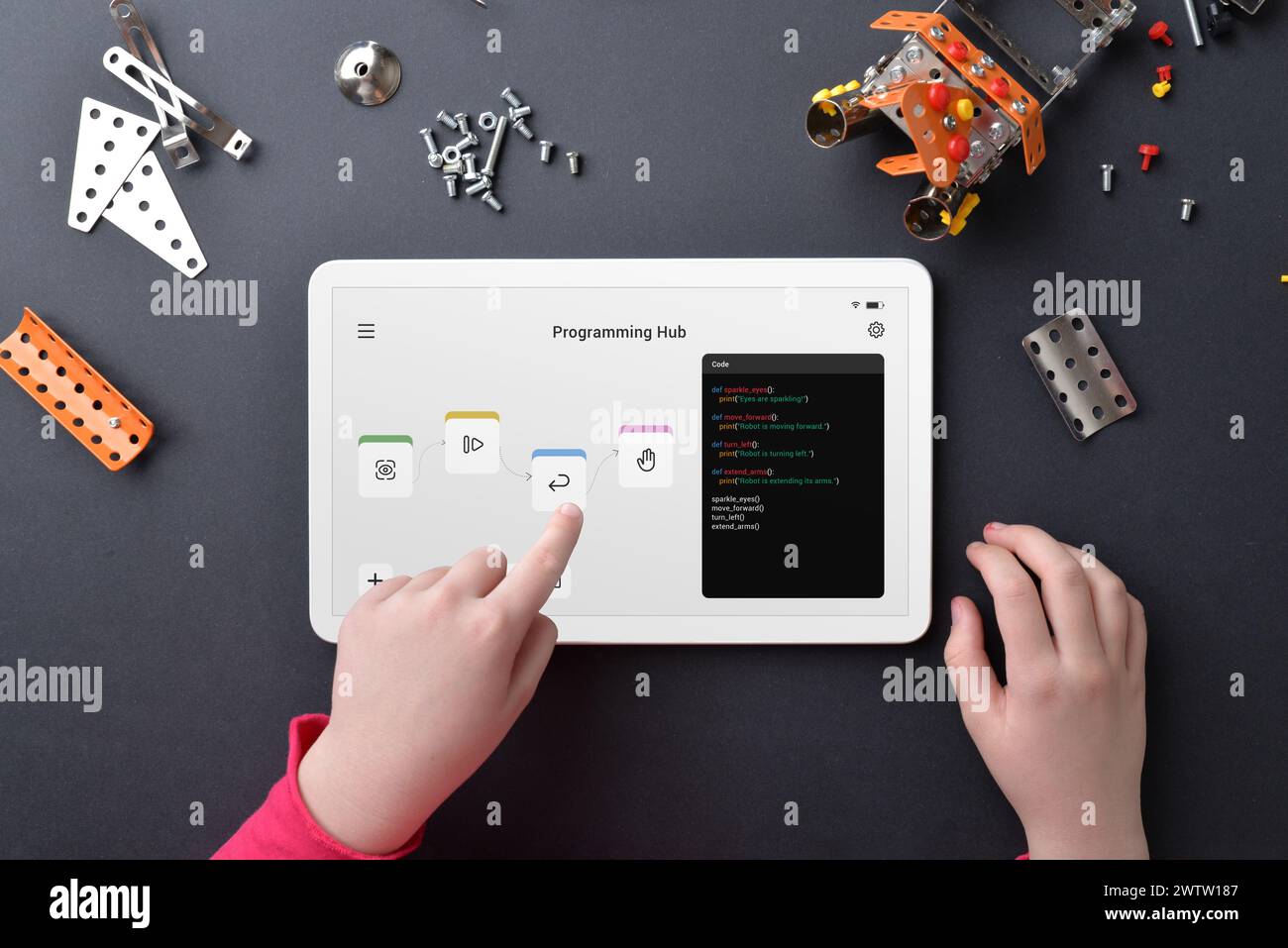 Robot de programmation enfant sur tablette au milieu de petites pièces sur la table de travail. Illustrer l'éducation, les compétences en programmation, la créativité et l'apprentissage pratique Banque D'Images