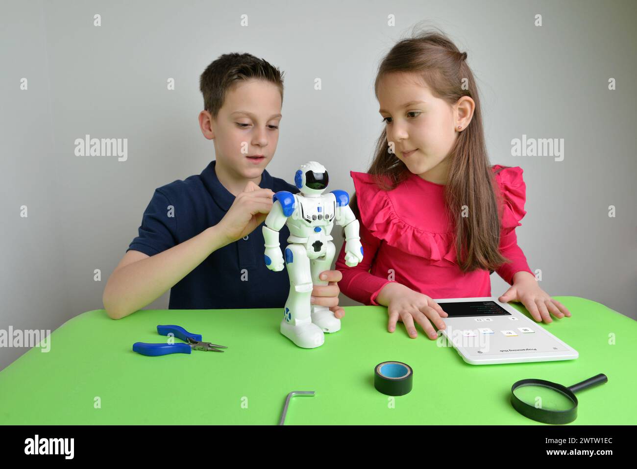 Fille et garçon assemblent un grand objet blanc sur l'établi, programmant ses fonctions. Concept de travail d'équipe, de technologie, d'apprentissage et d'innovation Banque D'Images