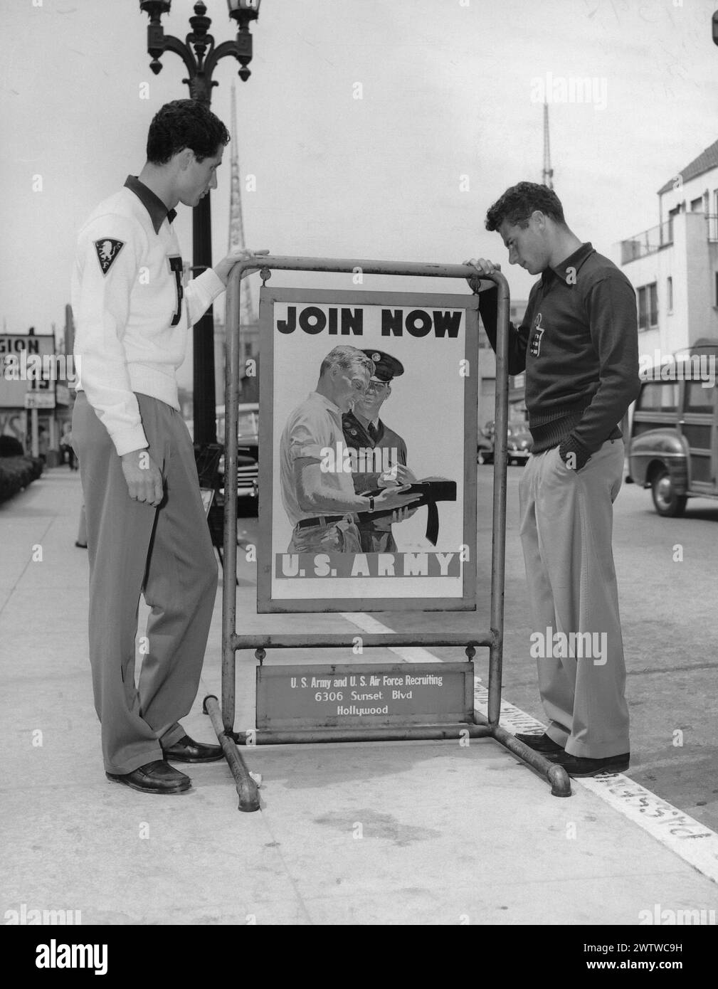 Deux adolescents bien habillés et épurés debout dans la rue à Hollywood, en Californie, regardant une affiche de recrutement de l'US Army & Air Force Banque D'Images