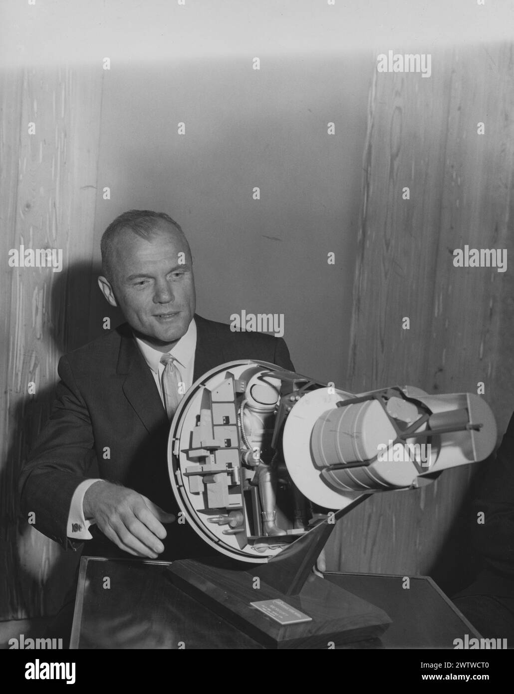 L'astronaute AMÉRICAIN John Glenn assis à une table avec une maquette de la capsule spatiale qu'il pilotera en orbite autour de la Terre Banque D'Images