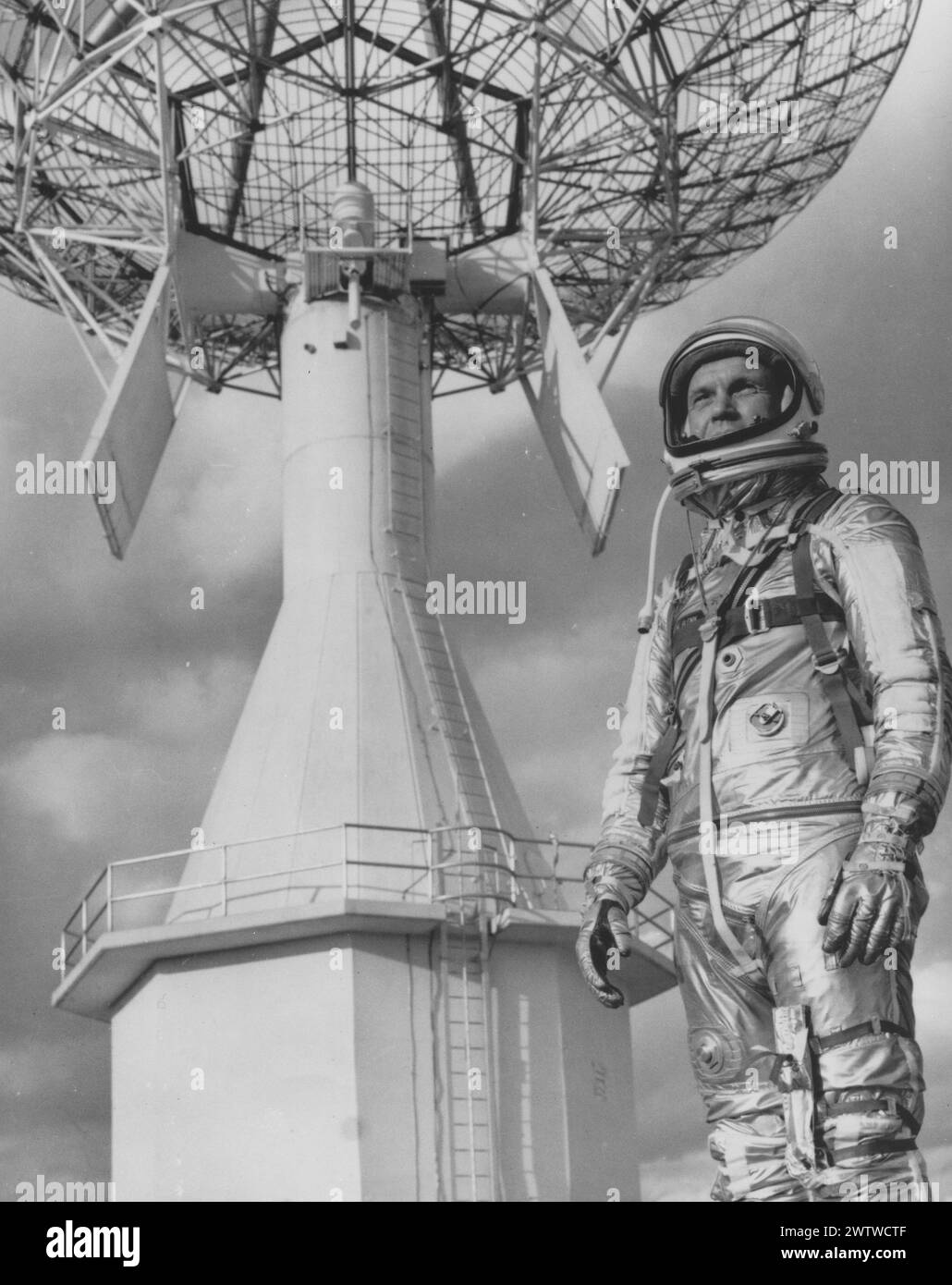 L'astronaute AMÉRICAIN John Glenn, portant ses gants de combinaison spatiale et son casque debout devant une grande antenne radio Banque D'Images