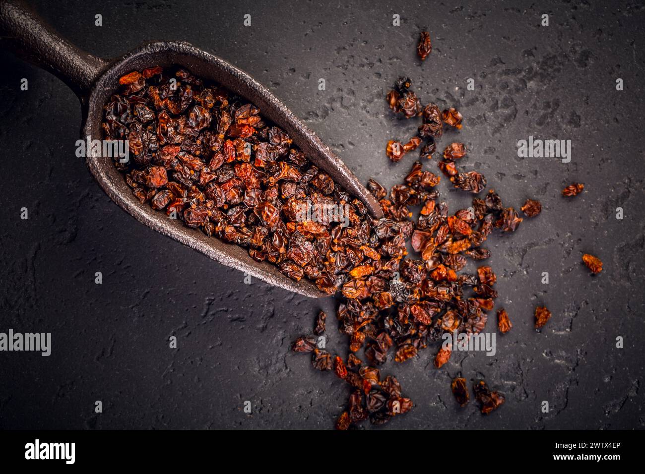berberis séché biologique et cuillère sur fond noir Banque D'Images
