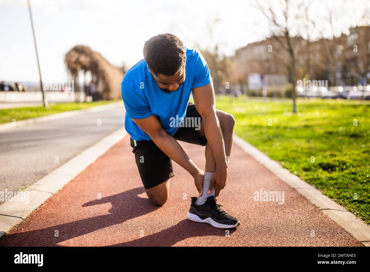 Un jeune homme afro-américain est blessé en faisant du jogging. Il s'est tordu la cheville. Banque D'Images