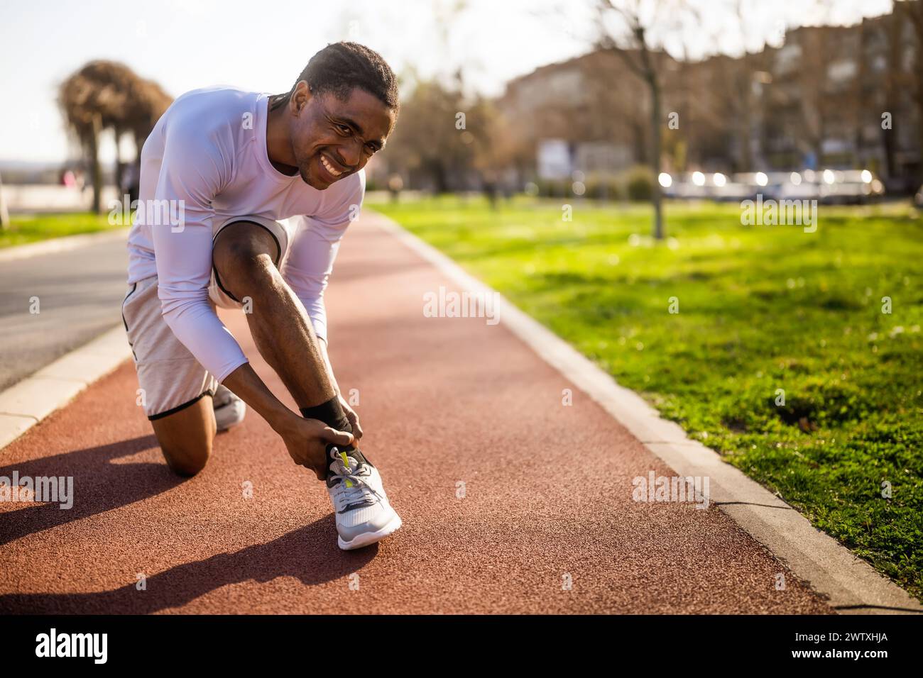 Un jeune homme afro-américain est blessé en faisant du jogging. Il s'est tordu la cheville. Banque D'Images
