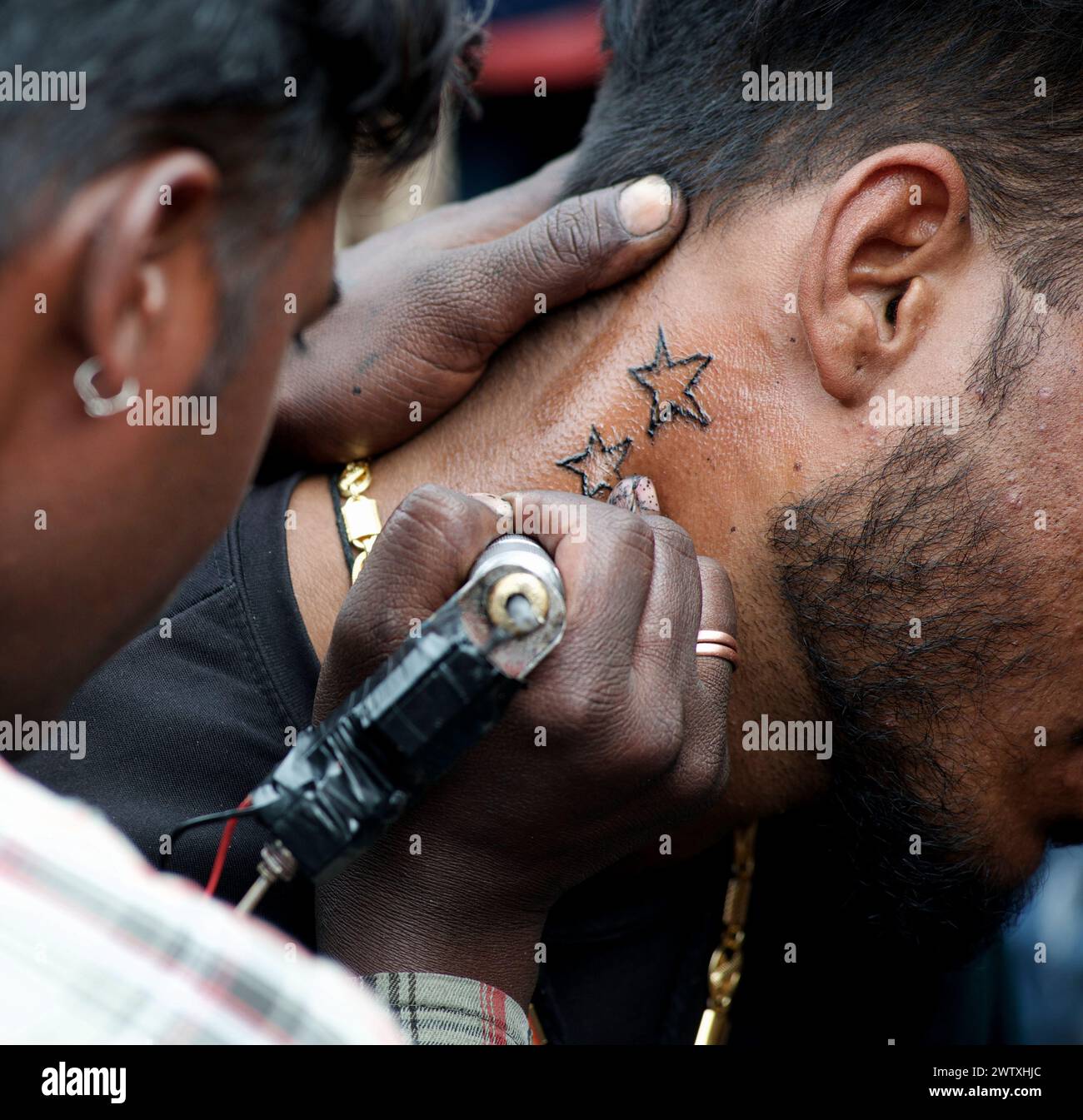 Tatoueur masculin, tatouage sur le cou d'un jeune homme barbu sur le sentier dans la ville de Pushkar, Rajasthan, Inde Banque D'Images