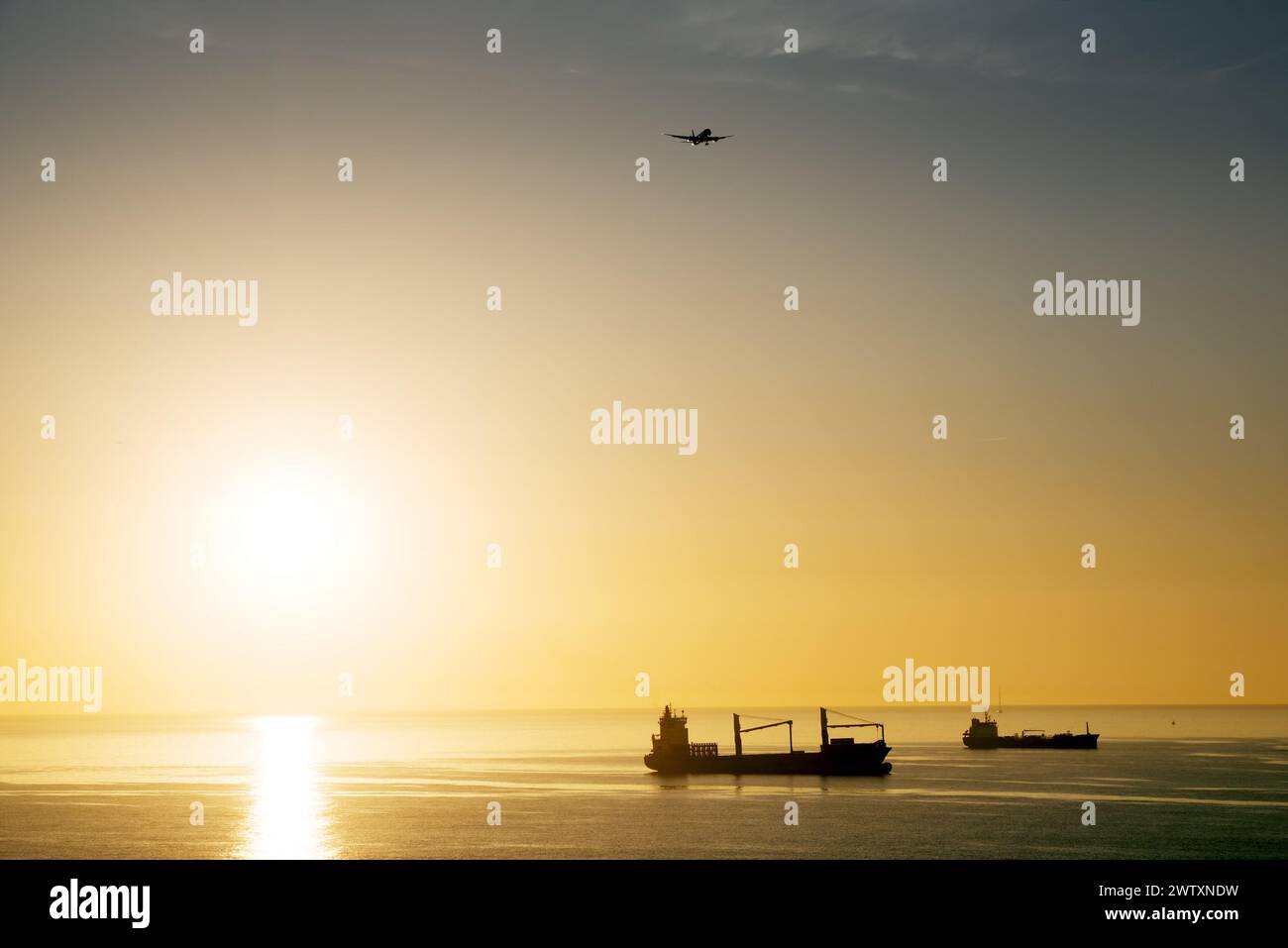 Vue sur la mer avec navires et avion lointains, lever du soleil Banque D'Images