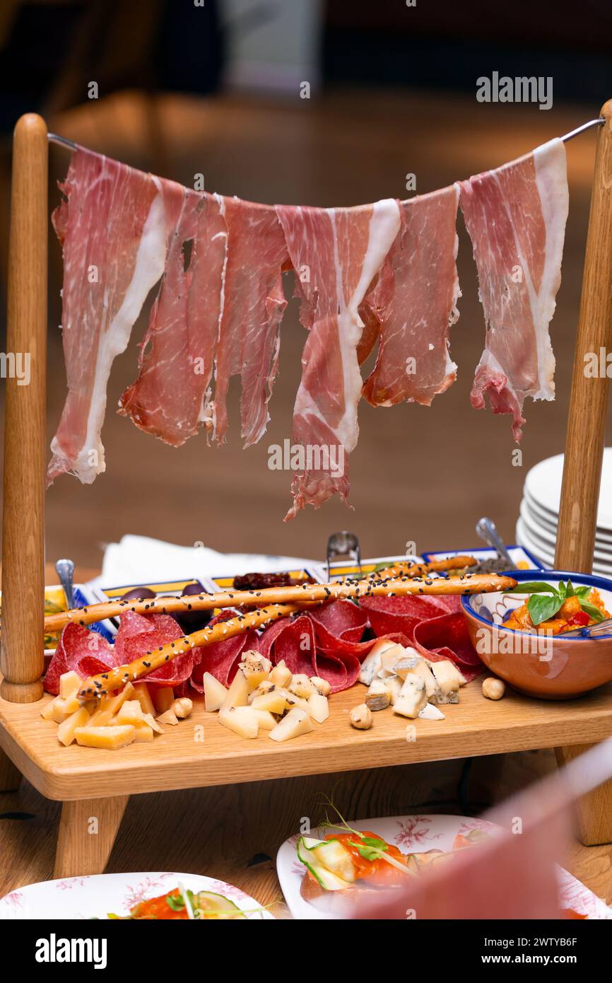 Service exquis original de snacks à la viande, jambon, jambon, salami, assortiment de fromages, olives, sauce. Antipasti sur la table dans un restaurant, italien Banque D'Images