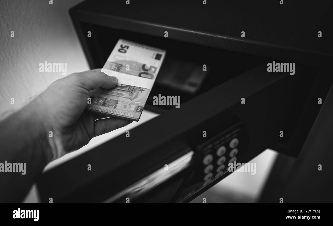 L'homme met ou prend des billets en euros dans un coffre-fort. Banque D'Images